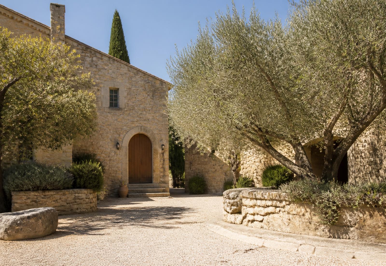 Entrée d’une villa provençale en pierre bordée d’oliviers