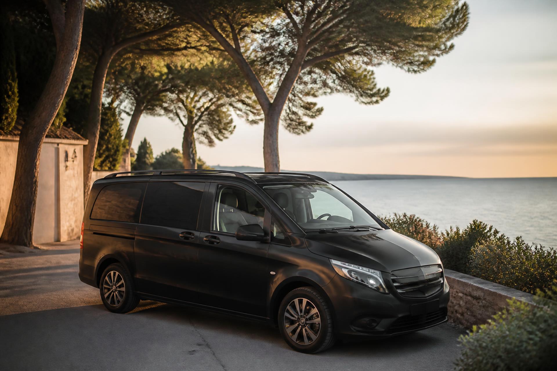 Véhicule noir premium Black Driving sur une route côtière de la Côte d'Azur au coucher du soleil